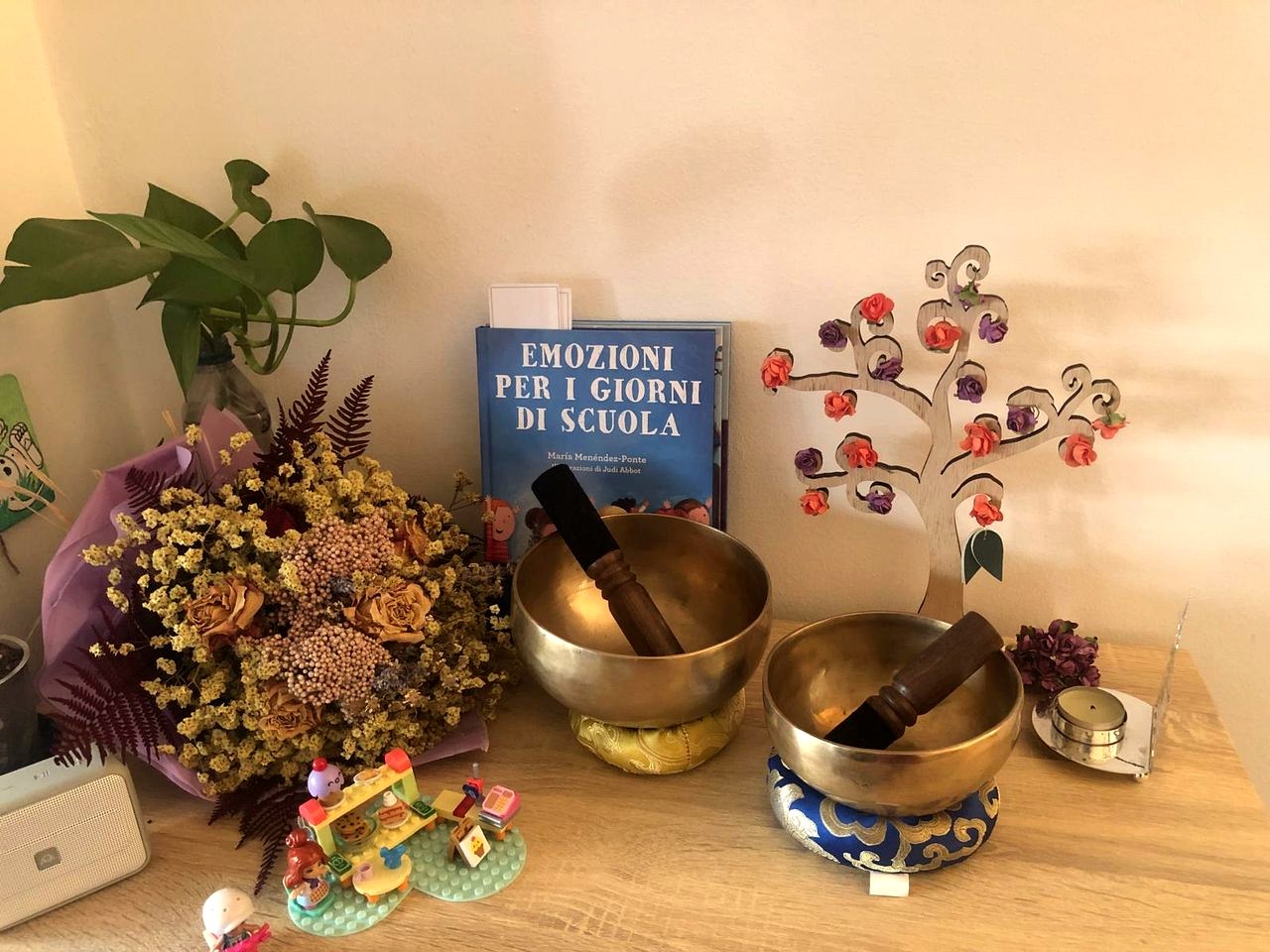 Un ripiano dello studio: campane tibetane, un libro sulle emozioni a scuola, piccoli giochi